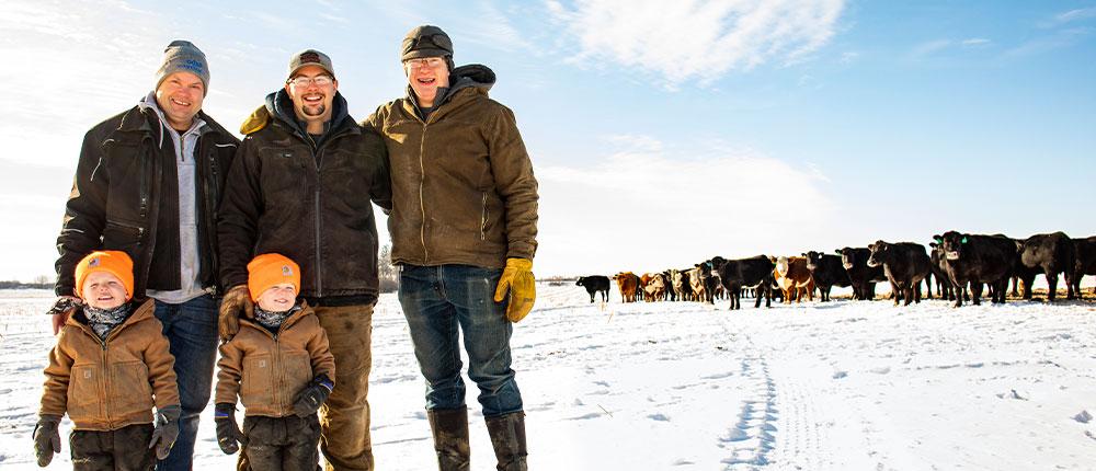 Richard Stadheim stands in a snow-covered cattle field with his sons, Garrett and Bennett, and Bennett’s young twin boys